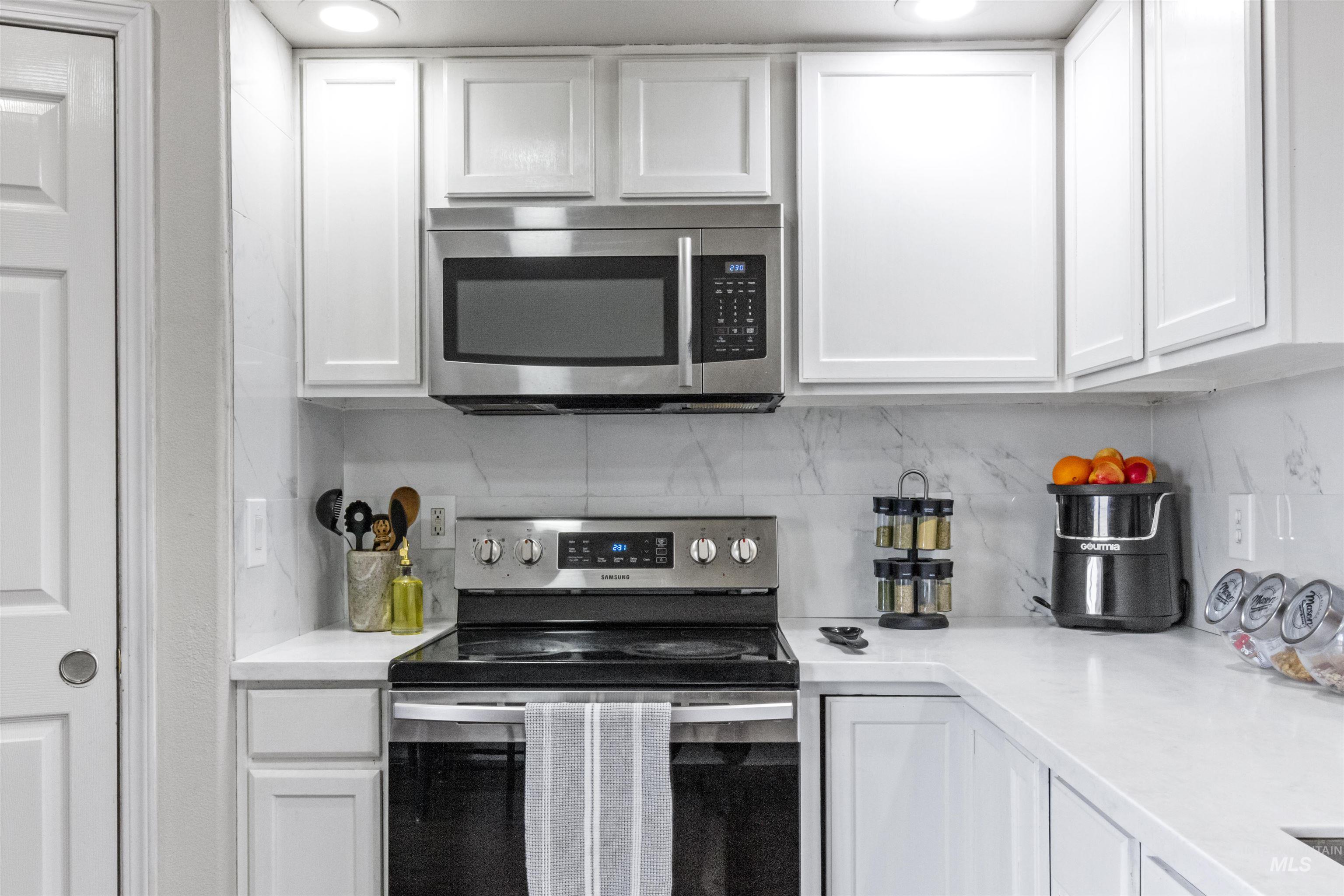 1823 Cambridge Street Caldwell, ID 83607 - Photo 2 of 10 Kitchen with stainless steel appliances, white cabinets, light stone counters, and backsplash