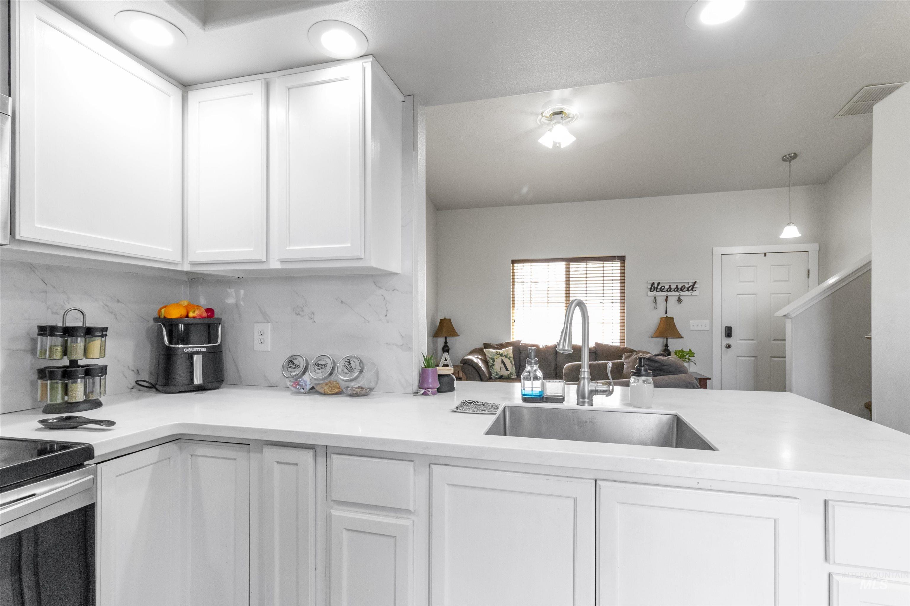 1823 Cambridge Street Caldwell, ID 83607 - Photo 10 of 10 Kitchen featuring white cabinetry, a peninsula, open floor plan, tasteful backsplash, and light stone counters