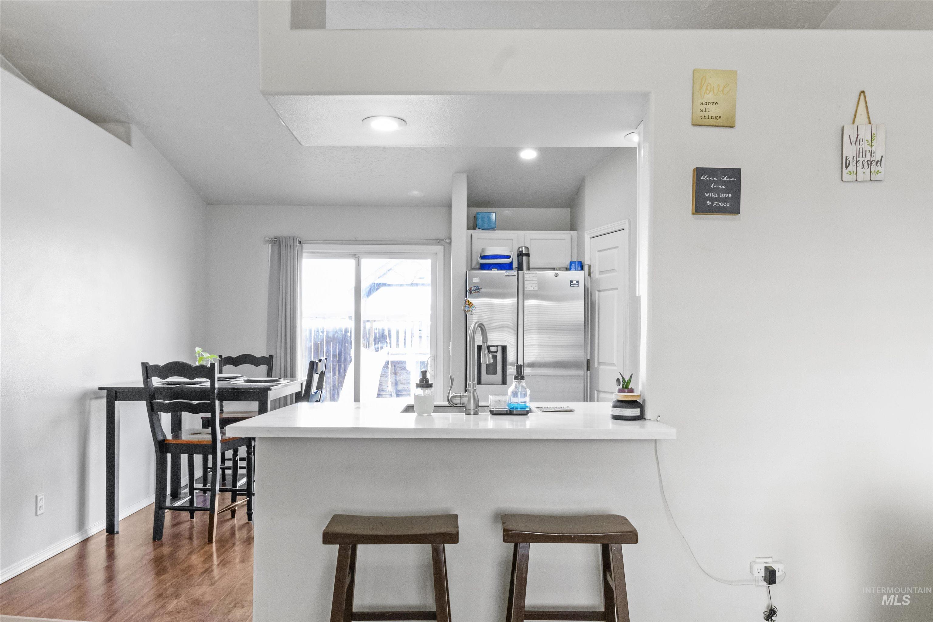 1823 Cambridge Street Caldwell, ID 83607 - Photo 4 of 10 Kitchen with a breakfast bar area, a peninsula, stainless steel fridge, white cabinets, and dark wood-style floors
