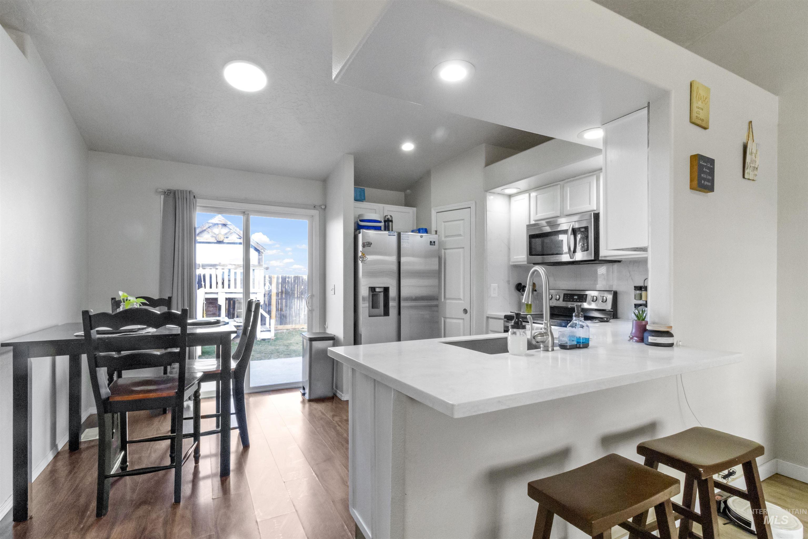 1823 Cambridge Street Caldwell, ID 83607 - Photo 8 of 10 Kitchen featuring white cabinets, a kitchen bar, a peninsula, stainless steel appliances, and dark wood-style floors