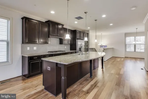 a kitchen with stainless steel appliances granite countertop wooden floors and wooden cabinets