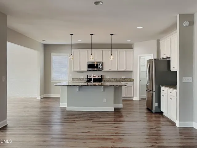 a kitchen with stainless steel appliances granite countertop a refrigerator a stove top oven a sink and cabinets