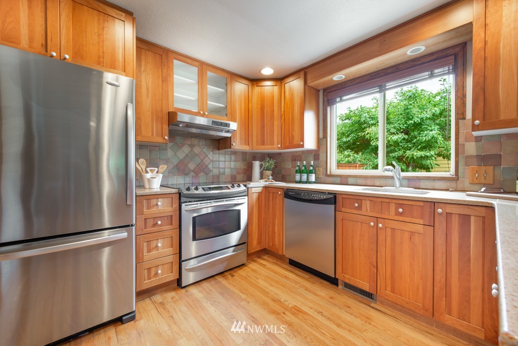 560 North 76th Street Seattle, WA 98103 - Photo 12 of 37 a kitchen with granite countertop white cabinets and white stainless steel appliances
