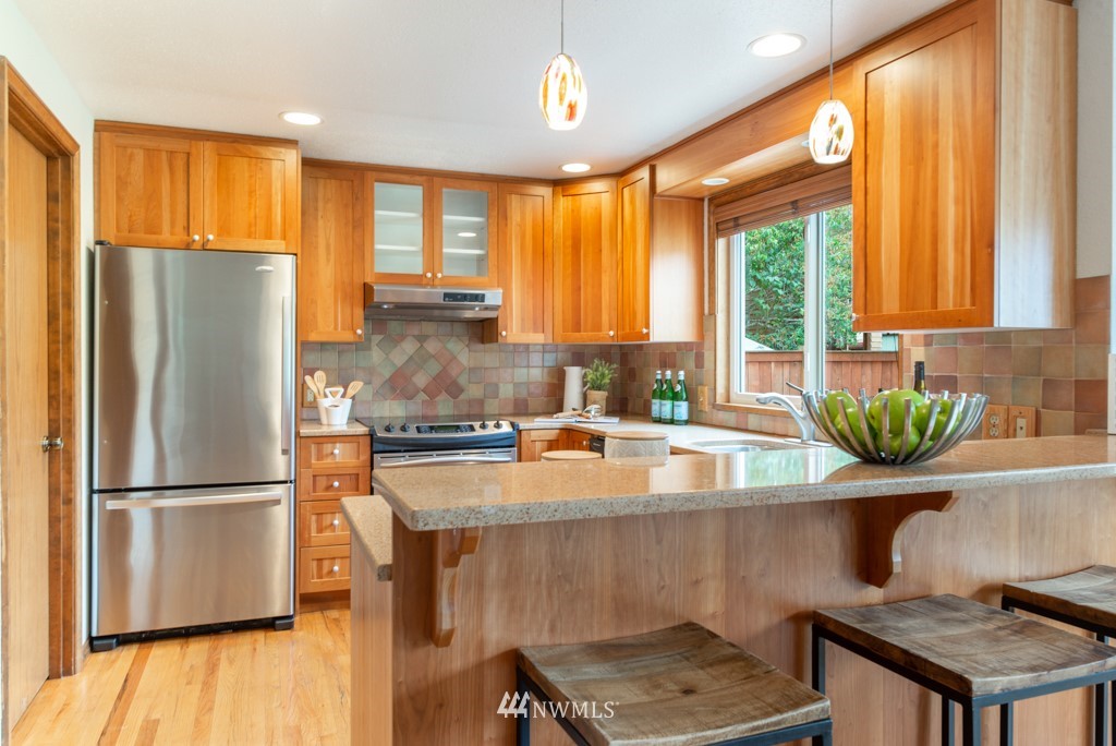560 North 76th Street Seattle, WA 98103 - Photo 13 of 37 a kitchen with stainless steel appliances granite countertop a refrigerator a sink dishwasher a stove and a dining table with wooden floor