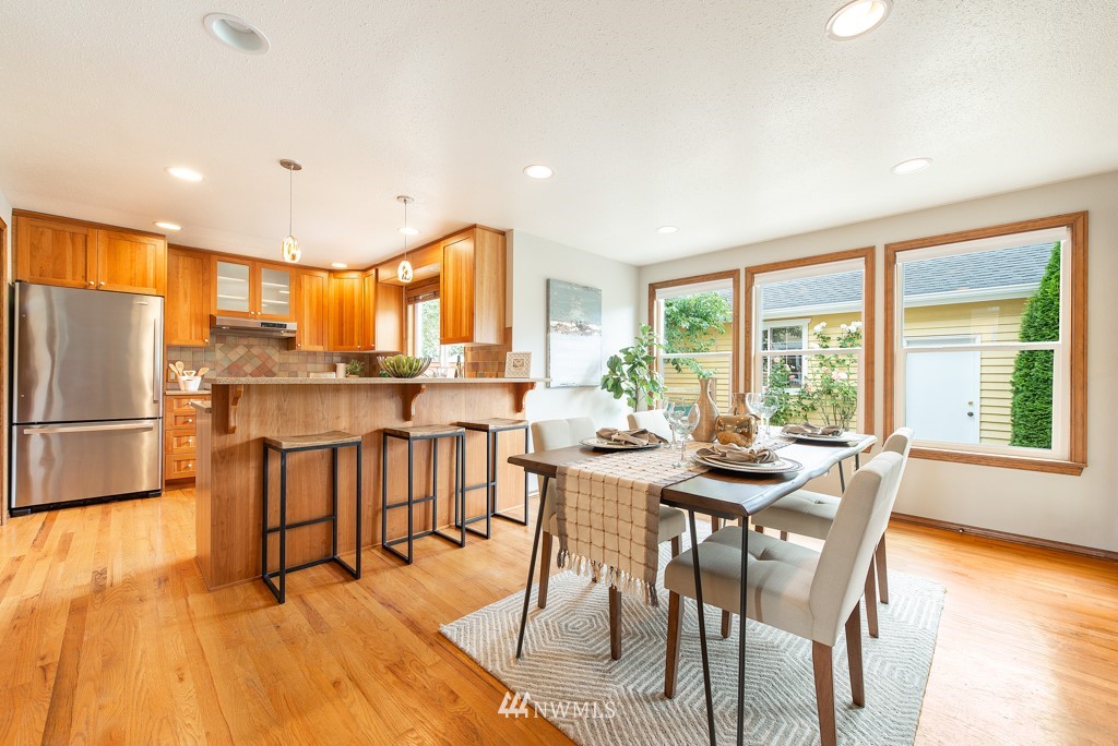 560 North 76th Street Seattle, WA 98103 - Photo 10 of 37 a dining room with stainless steel appliances granite countertop a stove a refrigerator a stove a dining table and chairs with wooden floor