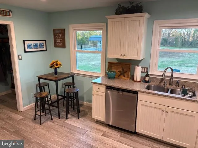 a kitchen with stainless steel appliances granite countertop a stove a sink dishwasher and a dining table with wooden floor
