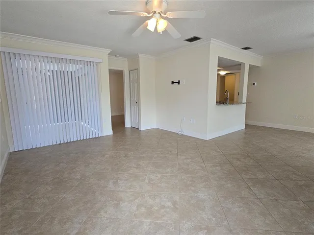 a view of an empty room with window and chandelier fan