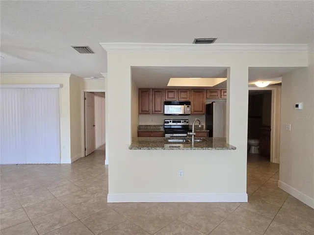 a view of kitchen with stainless steel appliances wooden floor and living room