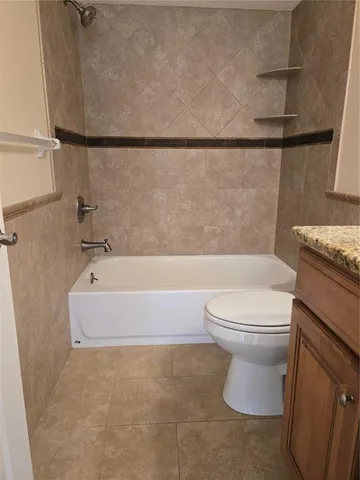 a bathroom with a granite countertop bathtub toilet and sink