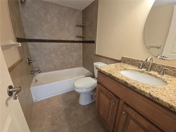 a bathroom with a granite countertop bathtub shower sink vanity and toilet