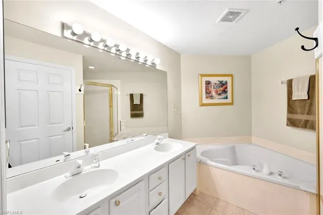 a bathroom with a tub a double vanity sink and a mirror