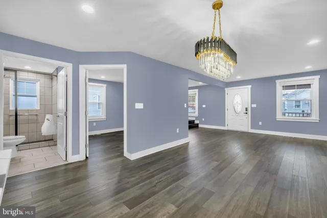 a view of a room with wooden floor chandelier and windows