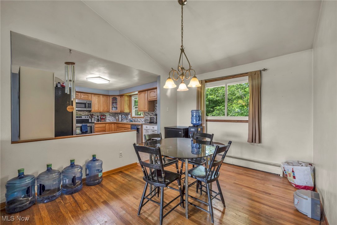 11996 Bower Road East Rochester, OH 44625 - Photo 11 of 49 Dining space featuring baseboard heating, wood finished floors, and lofted ceiling