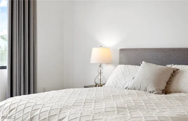 a large bed with a white comforter pillows and a chair