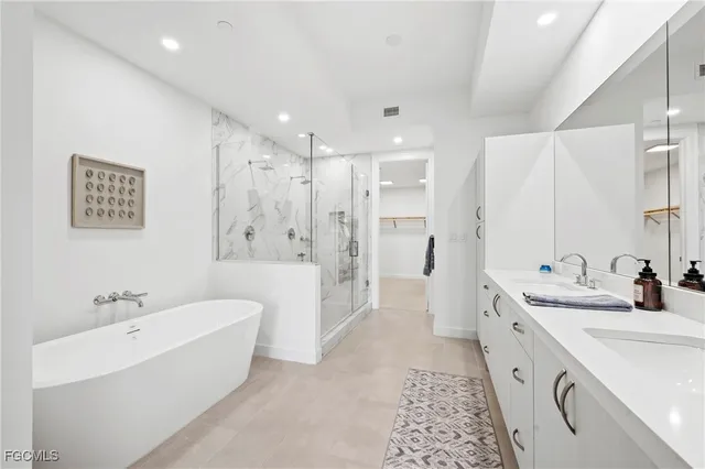 a bathroom with a double vanity sink a large mirror a shower and bathtub