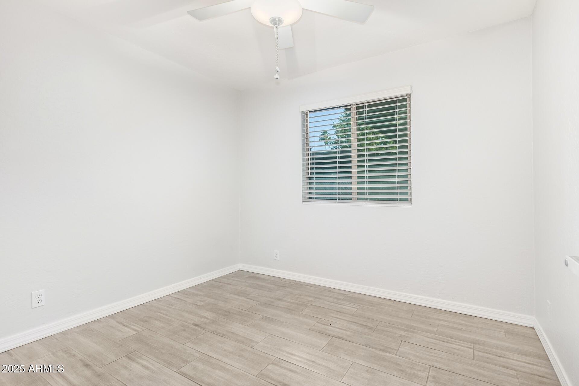 1619 West Peoria Avenue, Unit 2 Phoenix, AZ 85029 - Photo 7 of 8 a view of an empty room with wooden floor and a window