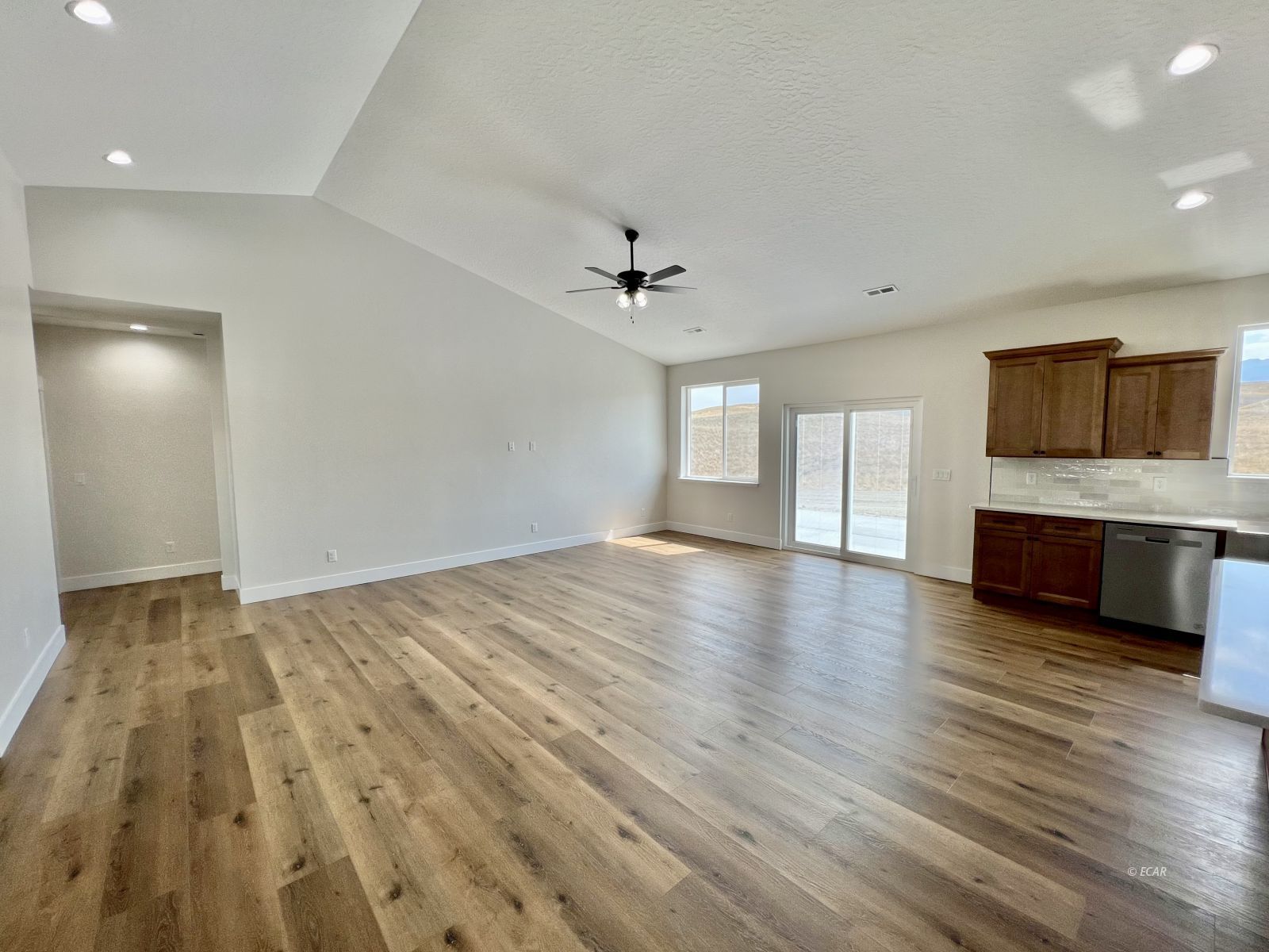 610 Ridgeway Drive Spring Creek, NV 89815 - Photo 9 of 33 an empty room with wooden floor and a kitchen