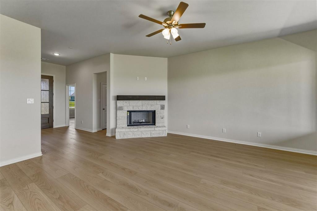 114 Hillview Trail Decatur, TX 76234 - Photo 12 of 27 Spacious living area featuring wood-finish flooring, a white brick fireplace with a dark wood mantel, and a ceiling fan with integrated lighting