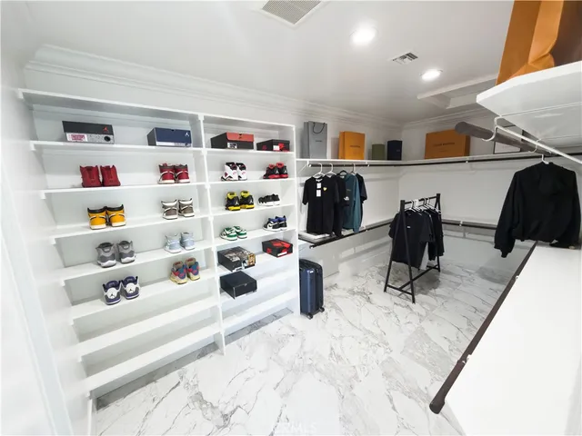 a bed sitting in a spacious bedroom next to a window and a larger closet