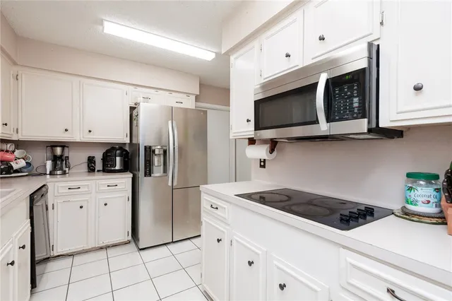 a kitchen with stainless steel appliances white cabinets white stove a microwave and a refrigerator