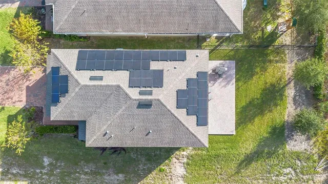 an aerial view of a house with a yard and a large tree
