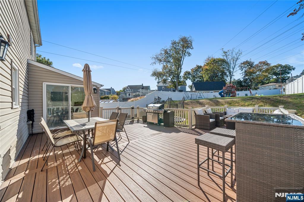 25 Glenview Road Nutley, NJ 07110 - Photo 43 of 49 a view of a roof deck with table and chairs a barbeque with wooden floor and fence