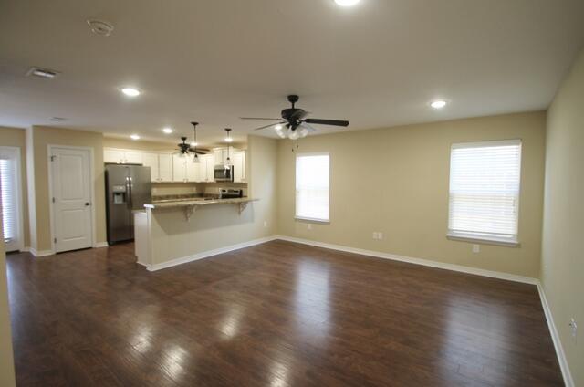 220 Wainwright Drive Crestview, FL 32539 - Photo 3 of 25 an open kitchen with white cabinets a refrigerator and wooden floor