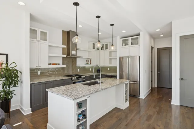 a kitchen with kitchen island granite countertop a sink stainless steel appliances and cabinets