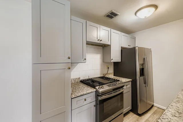 a kitchen with stainless steel appliances granite countertop a refrigerator and a stove