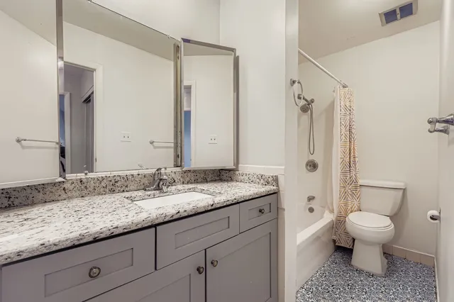 a bathroom with a granite countertop sink toilet mirror and a bathtub