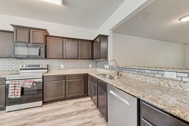 a kitchen with stainless steel appliances granite countertop a sink stove and cabinets