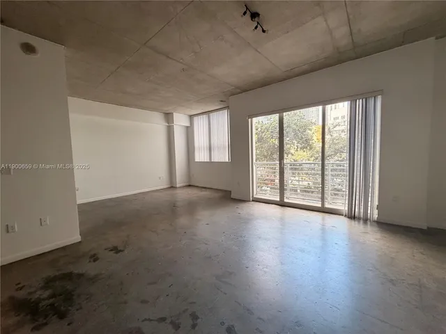 an empty room with wooden floor and windows with curtains