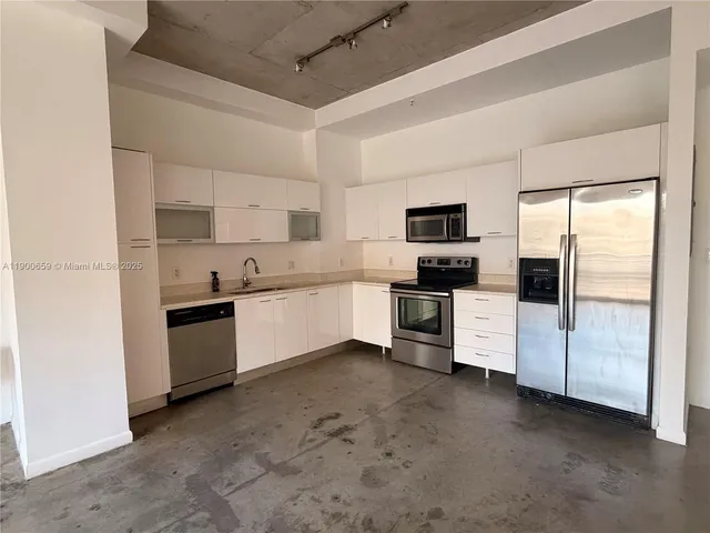 a kitchen with stainless steel appliances a refrigerator sink and white cabinets