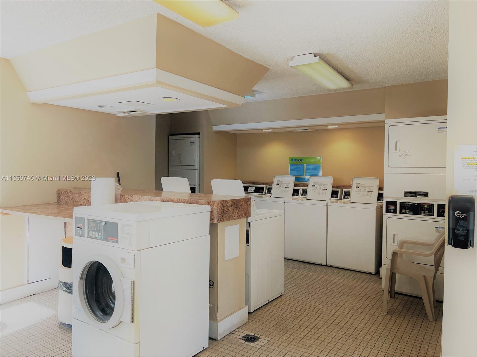 4361 West McNab Road, Unit 21 Pompano Beach, FL 33069 - Photo 13 of 18 a view of washer and dryer with kitchen in the background