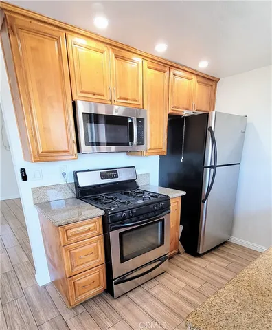 a kitchen with granite countertop a refrigerator stove and microwave