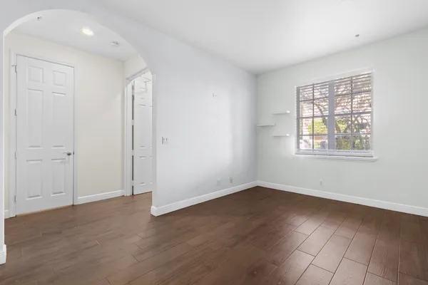 a view of an empty room with wooden floor and a window