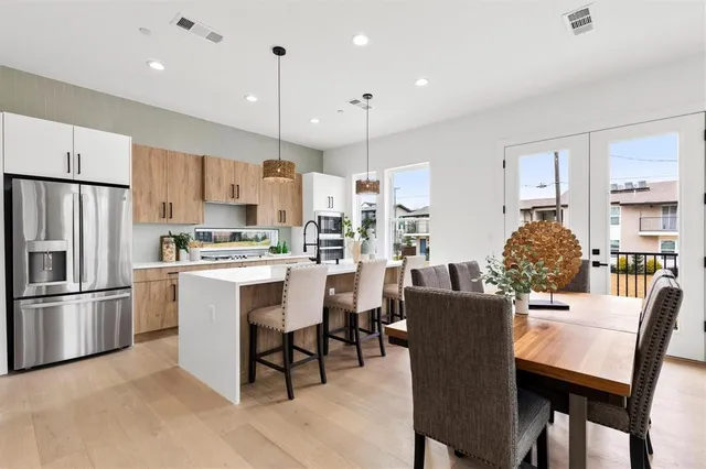 a kitchen with stainless steel appliances kitchen island granite countertop a dining table chairs refrigerator and sink