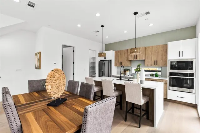 a living room with stainless steel appliances furniture a rug and a kitchen view