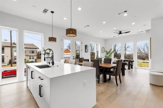 a open kitchen with stainless steel appliances granite countertop a sink a stove and a dining table with wooden floor