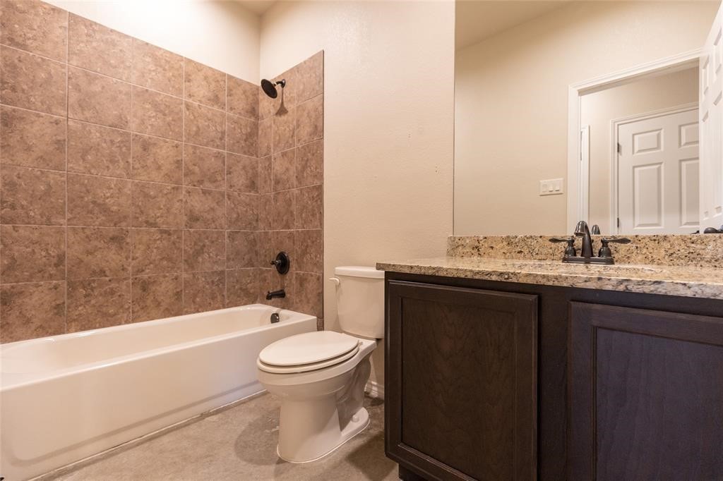 515 Jack Rabbit Lane, Unit A Buda, TX 78610 - Photo 5 of 16 a bathroom with a granite countertop toilet a sink and bathtub