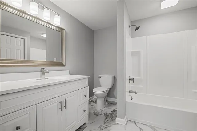 a bathroom with a granite countertop sink a toilet and bathtub