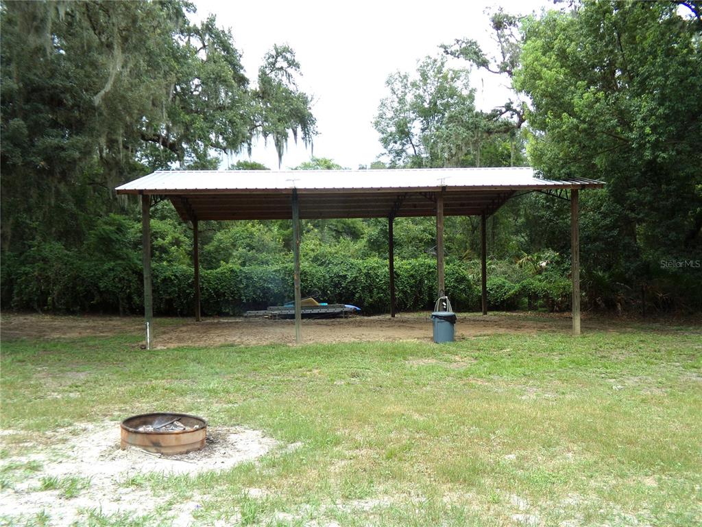 33068 Round Table Road Dade City, FL 33523 - Photo 19 of 82 a view of a garden with a bench and trees in the background