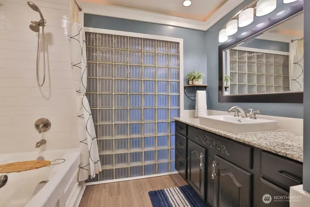 a bathroom with a granite countertop sink a mirror a bathtub and shower