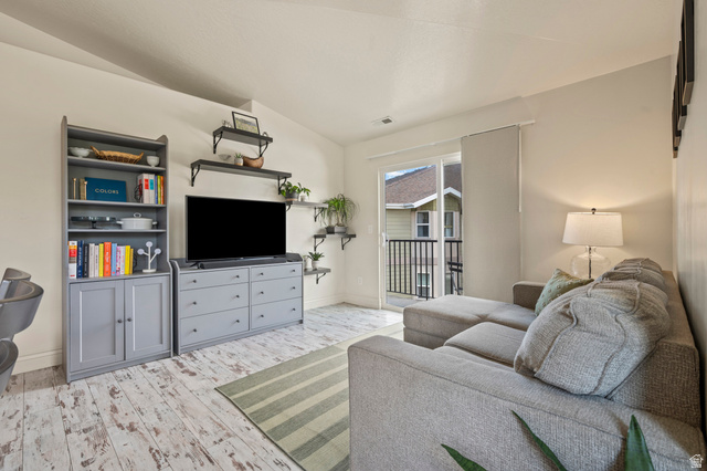 8248 South Resaca Drive, Unit J10 Sandy, UT 84070 - Photo 9 of 40 Living area featuring high vaulted ceilings, light wood-finish flooring, and a sliding glass door opening to a private balcony