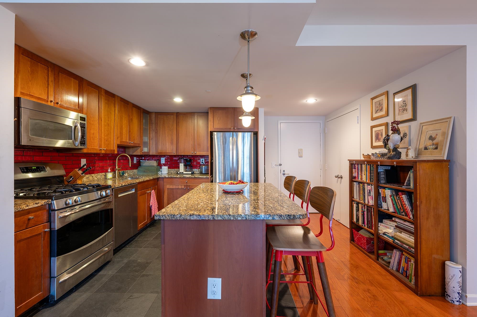 700 Grove Street, Unit 10A Jersey City, NJ 07310 - Photo 6 of 24 a kitchen with stainless steel appliances granite countertop a stove refrigerator and a dining table with wooden floor