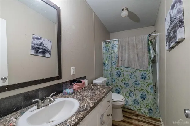 a bathroom with a granite countertop sink toilet and shower