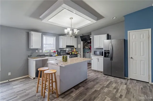 a kitchen with stainless steel appliances a refrigerator a sink dishwasher a stove and white countertops with wooden floor