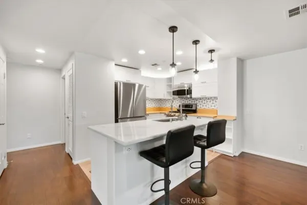 a kitchen with stainless steel appliances kitchen island a table chairs in it and wooden floors