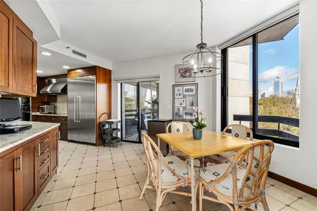 a kitchen with stainless steel appliances granite countertop a stove a refrigerator a kitchen island a sink cabinets and a dining table