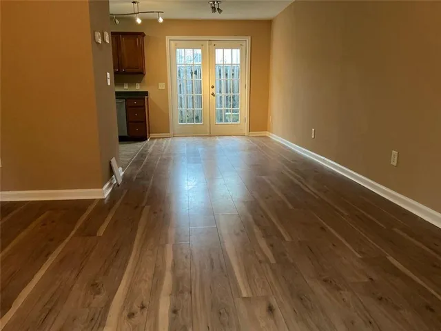 a view of a room with wooden floor and a kitchen